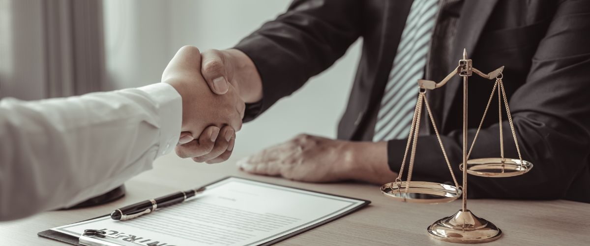 Legal Consultation for Name Change Process Two individuals shaking hands over a legal document with scales of justice, symbolizing the completion of a name change process.