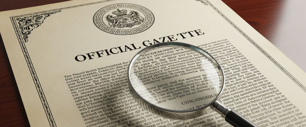 Official Gazette Notification Document Magnifying glass over an official gazette notification document with a seal.