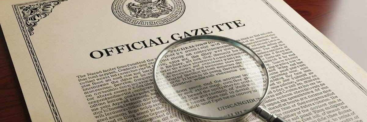 Magnifying glass over an official gazette notification document with a seal.